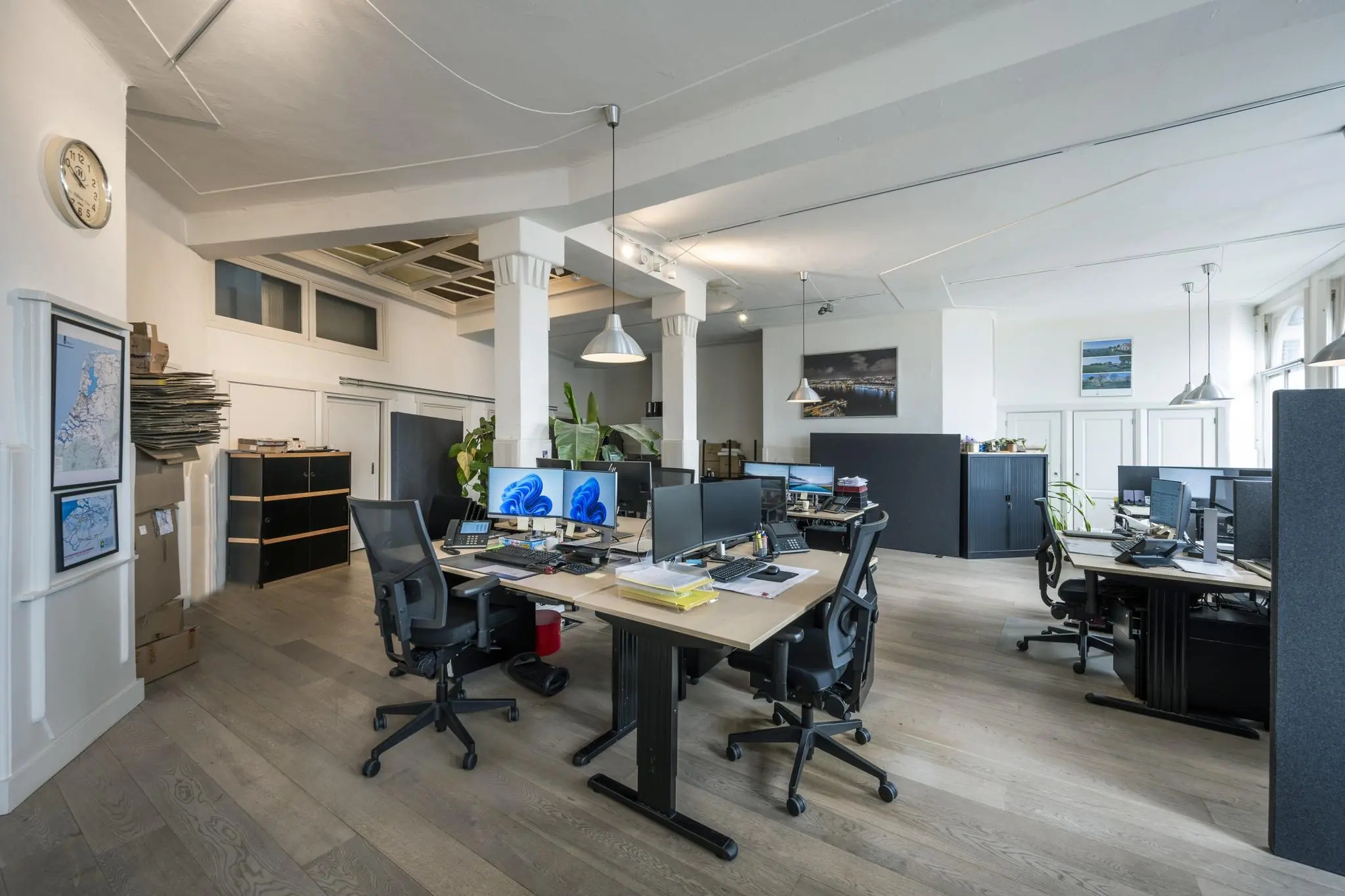 Modern kantoorinterieur aan de De Ruijterkade met open werkplekken, bureaus met computerschermen en natuurlijk licht.